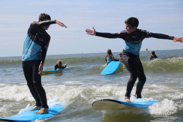 Twee jongens op surfplank in zee