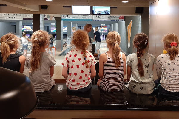 Kinderen zitten bij de bowlingbanen